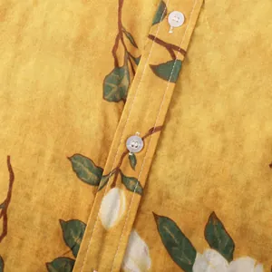 Dettaglio macro di camicia floreale gialla da uomo che mostra trama del tessuto e bottoni