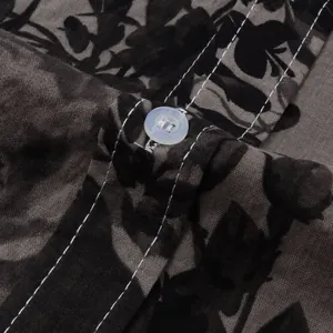 Detailed macro shot of white contrast stitching and resin button on floral men's shirt