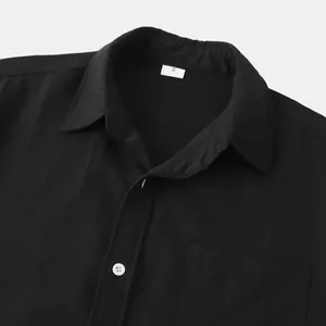 Detailansicht des schwarzen Leinenhemdkragens mit weißen Knöpfen und Reversdesign.