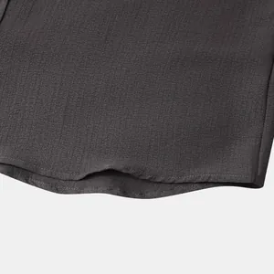 Close-up of fabric texture and hem stitching on dark grey men's short-sleeve shirt