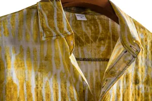 Detailed view of yellow and white tie-dye men's casual shirt with collar and linen texture