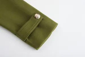 Dettaglio macro della manica di un cappotto di lana verde oliva con bottone dorato a stemma.