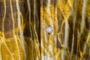 Macro view of men's casual floral shirt showing fabric texture and translucent button