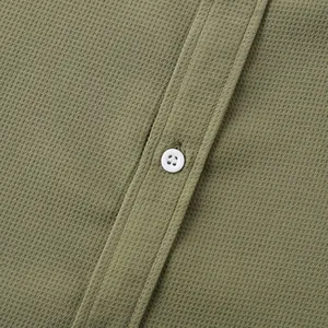 Close-up of olive green waffle knit men's shirt showing fabric texture and white button detail