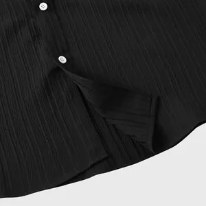 Detalle macro de la tela transpirable negra con textura y botones blancos de camisa masculina.