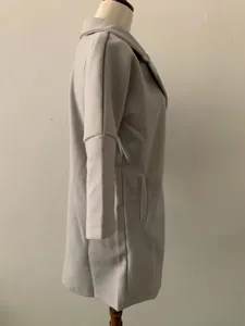 Détail de profil d'un manteau en laine gris pour femme avec col à revers et poches