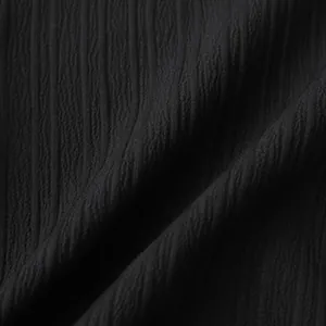 Detalle macro de tejido negro arrugado con pliegues verticales y suaves ondulaciones.