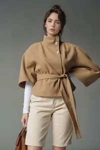 Modieuze camelkleurige wollen poncho met hoge kraag en ceintuur, zijaanzicht van model.