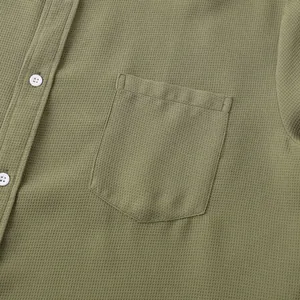 Detail of olive green waffle texture men's shirt showing chest pocket and buttons