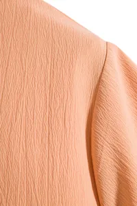 Macro view of textured apricot fabric and shoulder seam on a men's casual short-sleeve shirt