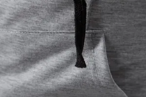 Gros plan détaillé d'un gilet de sport gris pour homme avec cordon noir et couture de poche.