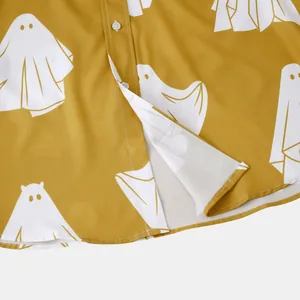 Dettaglio dell'orlo e dei bottoni di una camicia gialla con stampa di fantasmi bianchi.