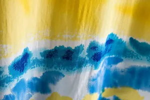 Macro detail view of vibrant blue and yellow tie-dye fabric texture on casual shirt