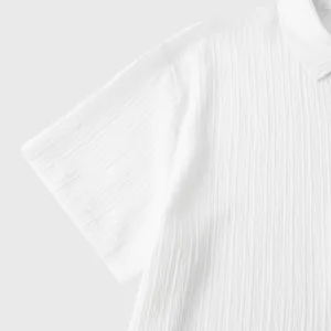 Primer plano de la tela blanca texturizada de una camisa de manga corta para hombre con cuello