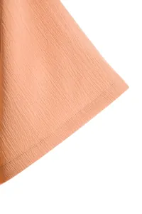 Macro detail showing the textured peach fabric and fine stitching on a men's summer shirt