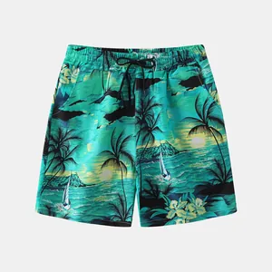 Close-up detail of vibrant tropical palm tree and sailboat print on teal beach shorts