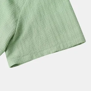 Close-up of light green textured seersucker fabric on a men's short sleeve shirt detail