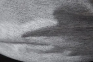 Gros plan sur la texture du tissu gris chiné respirant pour gilet de sport homme