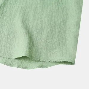 Close-up of light green textured fabric hem on a men's summer short sleeve shirt