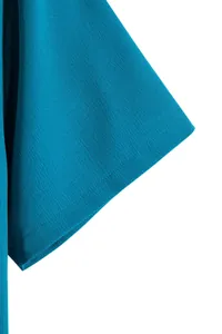 Detail view of a teal blue short sleeve shirt showing textured fabric and stitching.