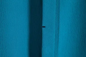 Close-up detail of teal textured fabric and buttonhole on a men's summer shirt.