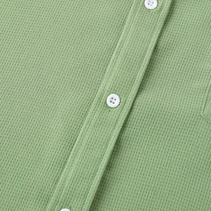 Macro detail of sage green waffle knit fabric and white buttons on a men's casual shirt
