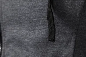 Gros plan du tissu chiné gris respirant et du cordon noir sur le gilet de sport pour