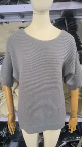 Détail d'un élégant pull en maille grise avec col rond et manches chauve-souris.
