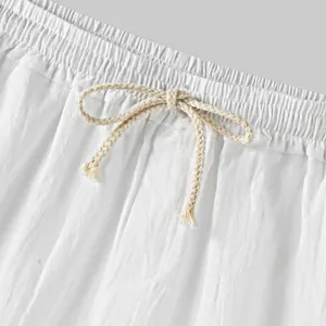 Close-up of white cotton linen shorts featuring elastic waistband and braided drawstring