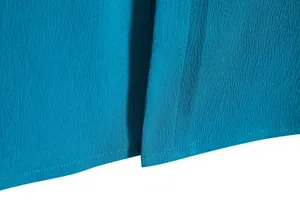 Close-up of textured teal fabric showing fine stitching and crinkled crepe material detail