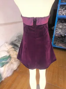 Detailed back view of a purple velvet strapless dress on a mannequin in a warehouse.
