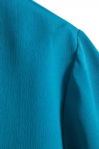 Detailed macro shot of textured peacock blue fabric on a men's short sleeve shirt
