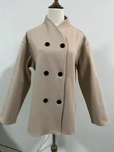 Vista frontale dettagliata di un elegante cappotto di lana beige doppiopetto su un manichino.