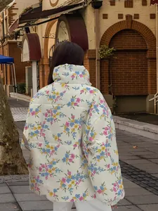 Back view detail of a white oversized puffer jacket featuring vibrant floral prints