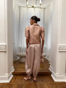 Vista posteriore di eleganti pantaloni a lanterna in raso rosa con un top in broccato