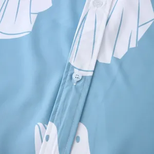 Dettaglio ravvicinato dei bottoni bianchi e del tessuto di una camicia a fiori azzurra