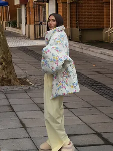 Model wearing a loose floral puffer jacket and yellow pants on a brick wall street background