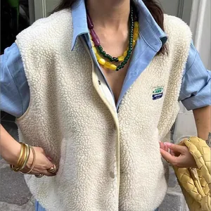 Close-up of beige fleece vest worn over a blue shirt with colorful beads.