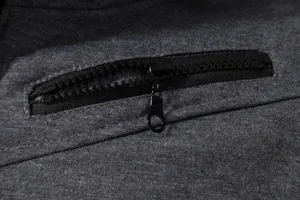 Détail macro de la fermeture éclair noire durable sur un gilet de sport pour homme.