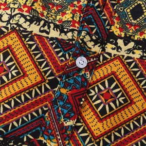 Macro view of Hawaiian print shirt showing fabric texture and white button detail.