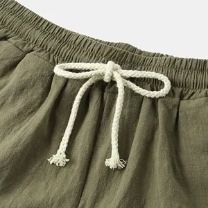 Macro detail of olive green cotton linen shorts featuring cream braided drawstring waistband