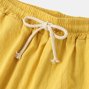 Gros plan d'un short en lin jaune avec cordon de serrage tressé blanc et taille élastique.