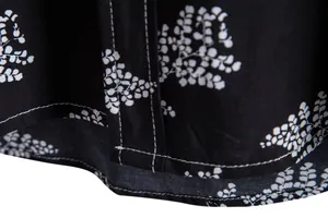 Detailed macro view of the stitching and white leaf print on a black floral casual shirt