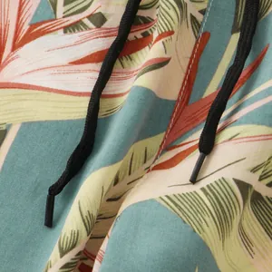 Close-up detail of tropical palm print fabric and black drawstring on beach shorts