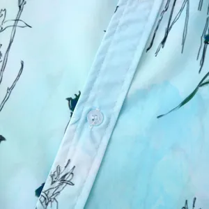 Détail rapproché du tissu fleuri bleu clair d'une chemise hawaïenne et d'un bouton