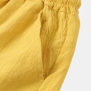 Détail macro de short de plage jaune en coton et lin montrant la texture du tissu et la poche