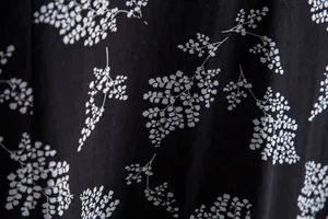 Macro detail of men's floral shirt showing white fern botanical print on black fabric