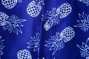 Macro view of blue Hawaiian shirt featuring white pineapple prints and clear button