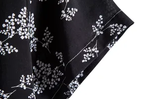 Close-up detail of white floral pattern and stitching on black men's short sleeve shirt