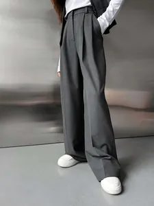Gros plan sur un pantalon de tailleur large gris foncé à taille haute plissée élégante.